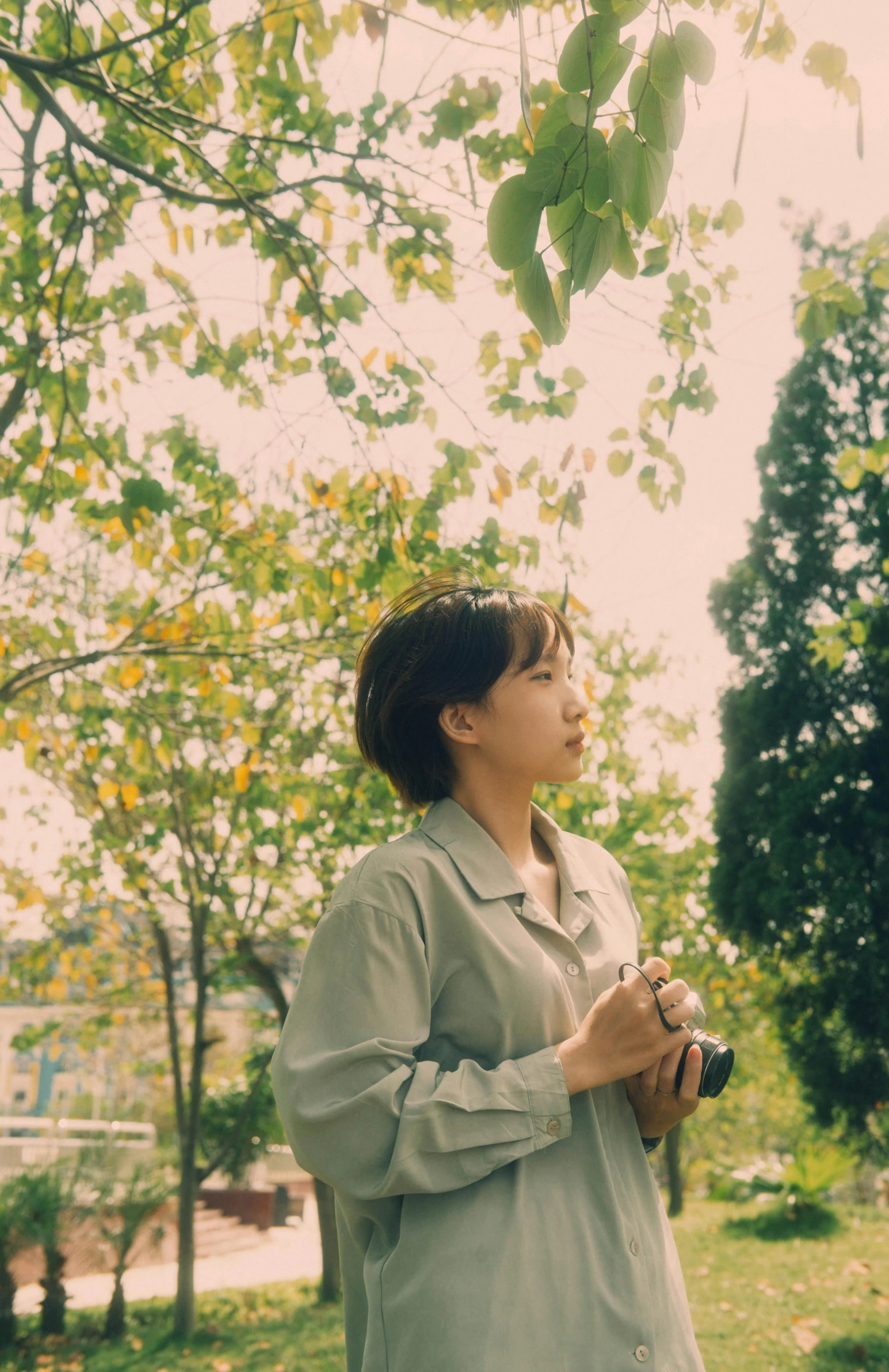 a woman standing in the grass holding a camera