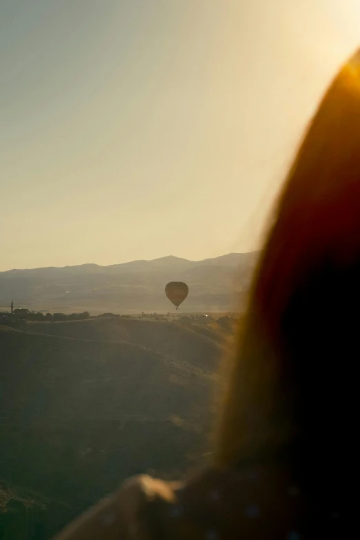 a person flying a balloon in the sky with a couple of people watching