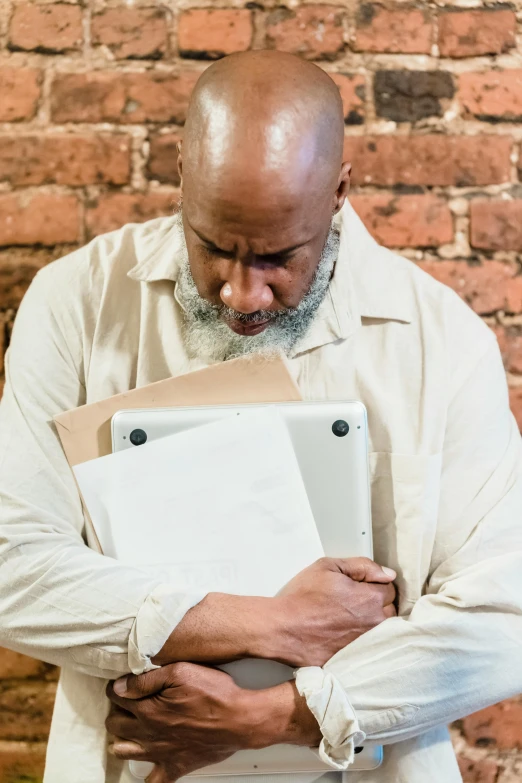 a man holding two ipads against a brick wall