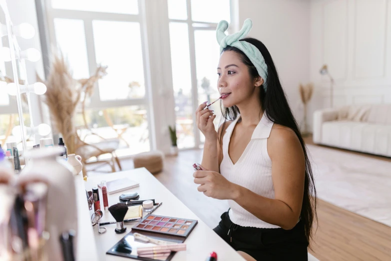 a woman putting on her makeup brushes sitting at a desk