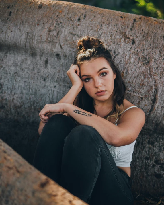 a woman sitting on a stone slab in black pants