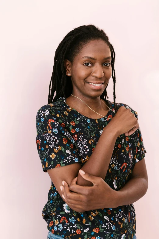 woman smiling with dread locks, against pink background