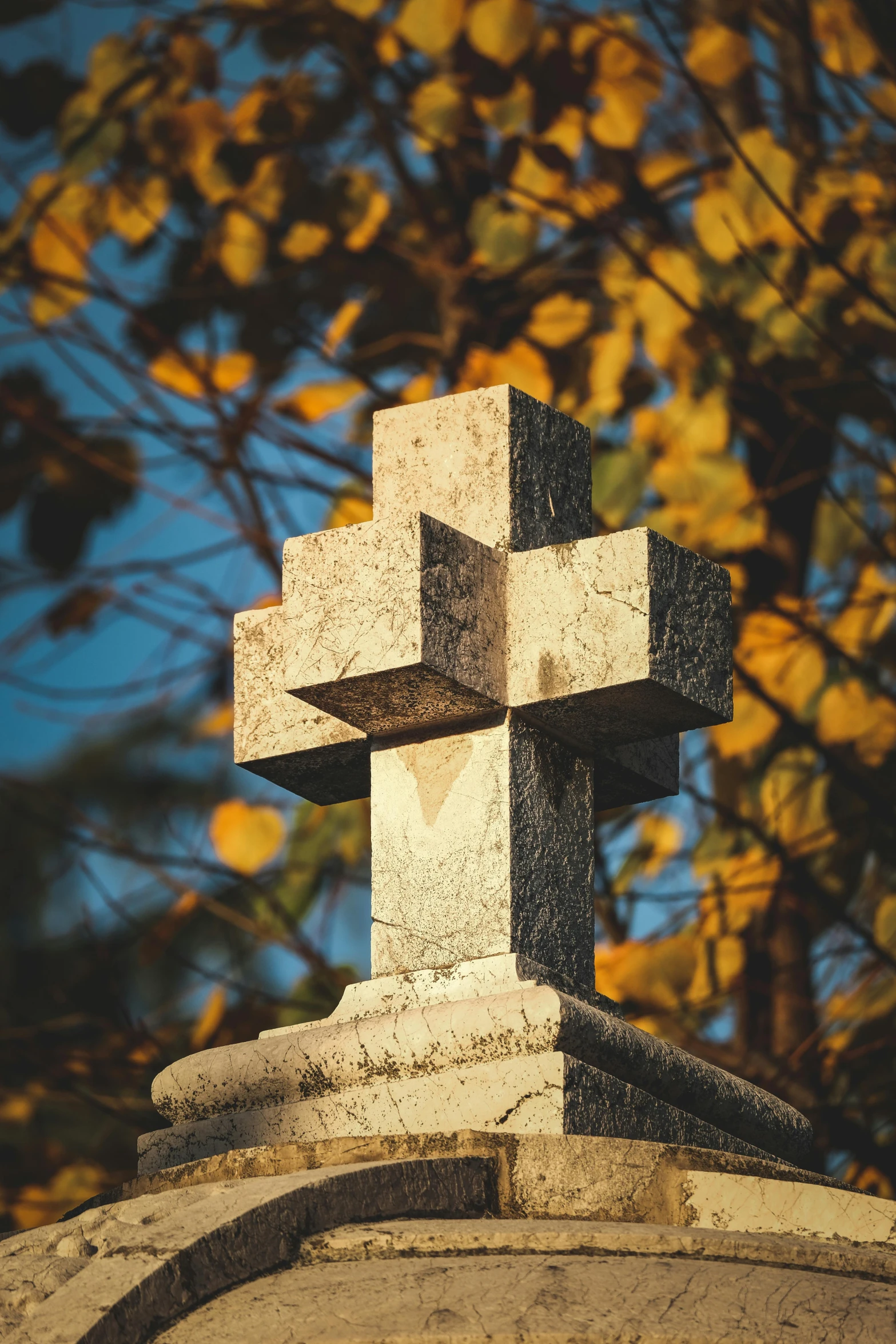 a cement cross is perched atop a cemetery wall