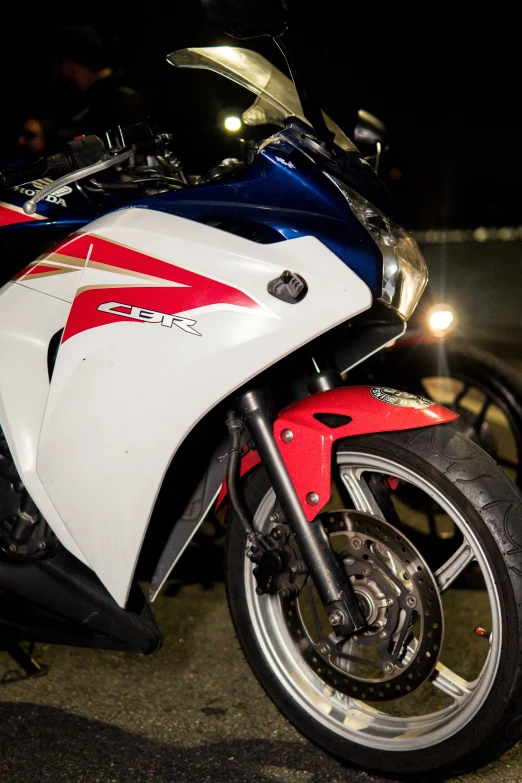 a red, white and blue motorcycle parked on the road