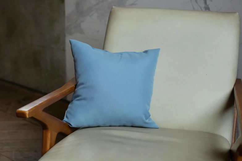 a blue pillow on a white chair near a beige chair