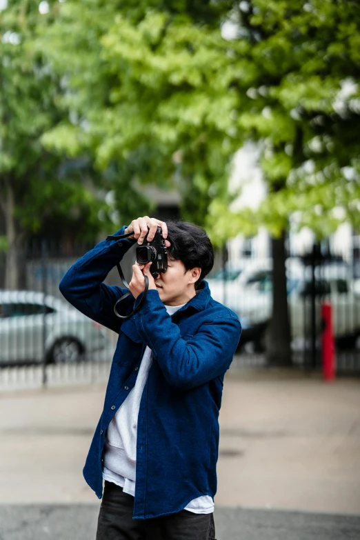 the young man is taking a pograph while holding up his camera