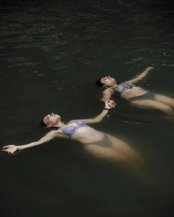 two young women in blue bathing suits are floating in the water