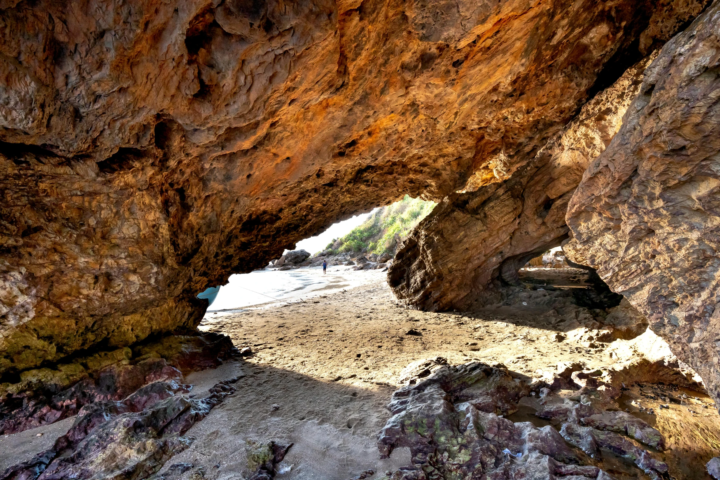 the inside view of a rocky cave looking out into the ocean