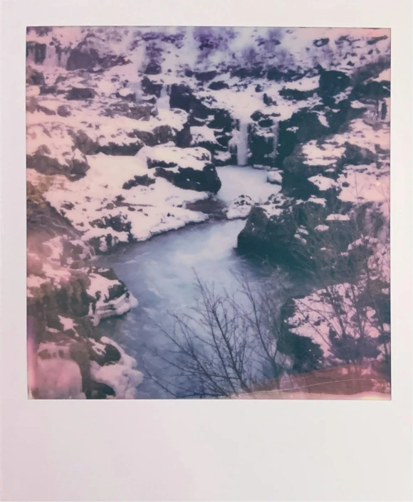 the polaroid print features an image of a lake with small waterfalls