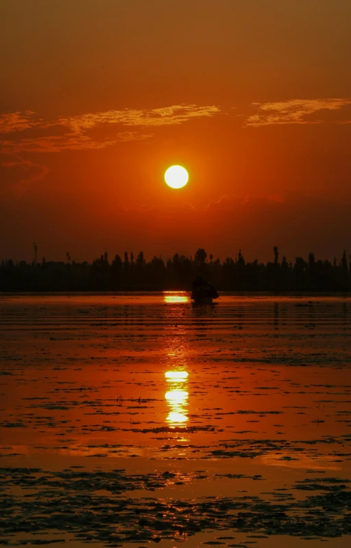 a small boat is floating in a lake as the sun sets