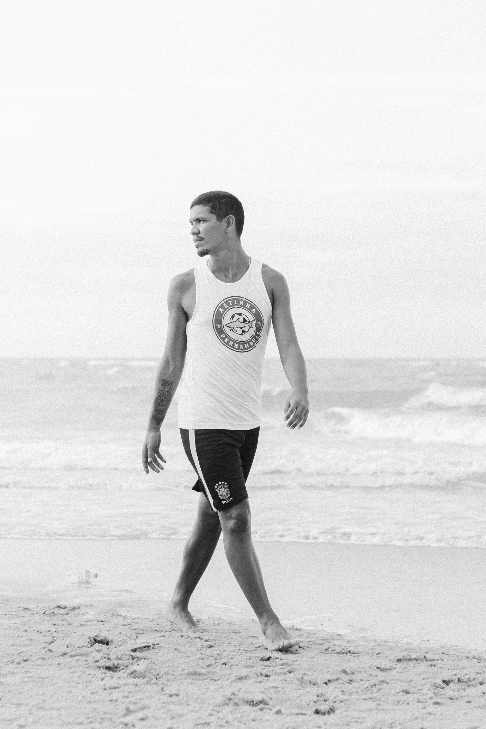 a man walking along the beach in shorts