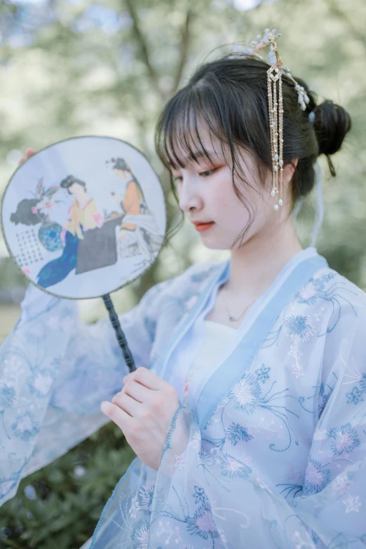 a woman wearing an asian - style kimono with a fan
