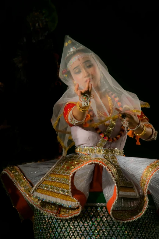 a woman in a white veil and outfit sits atop a large object