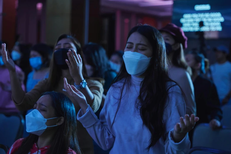 a large group of people wearing masks and talking on their cell phones