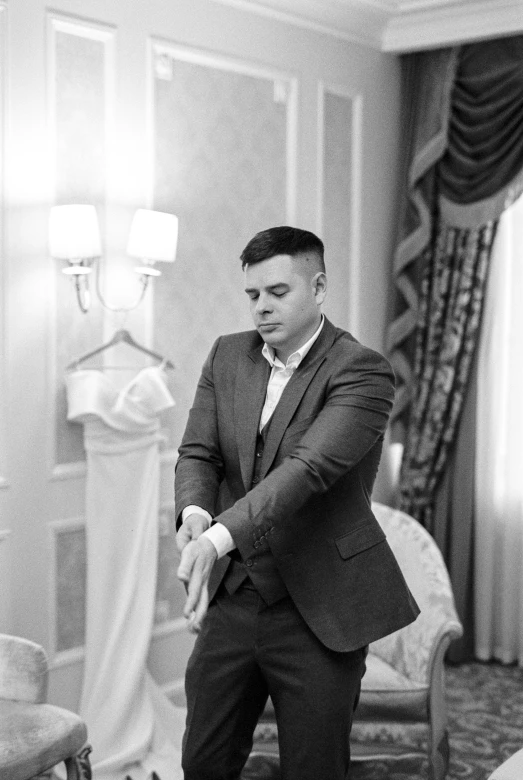 a man in a suit and tie standing next to a bed