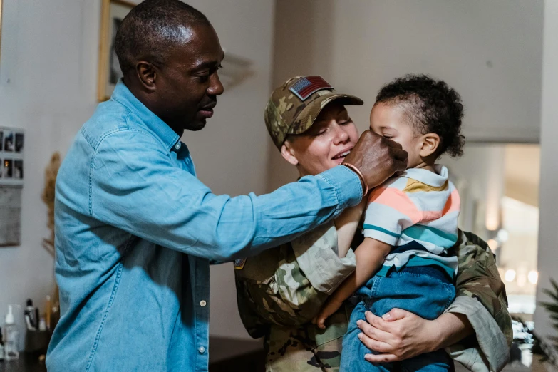 a man holding his son is talking to some soldiers