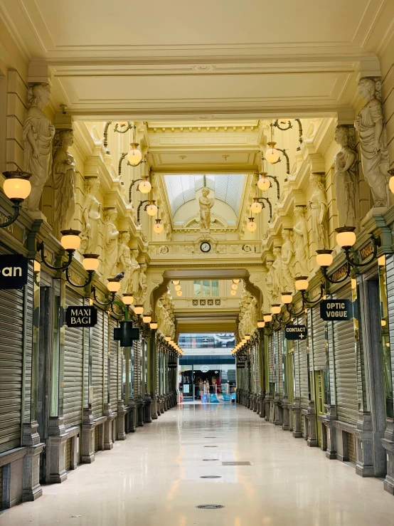 an empty corridor leading to a building with arches and a clock on it