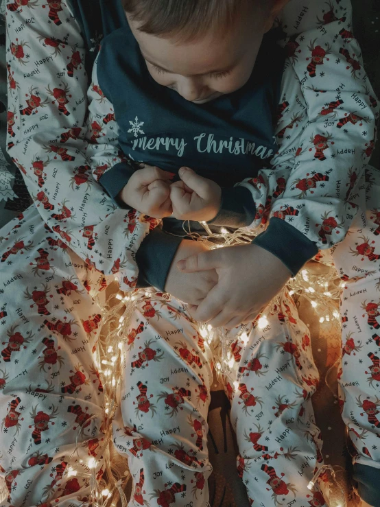 the child is sleeping in his pajamas next to christmas lights