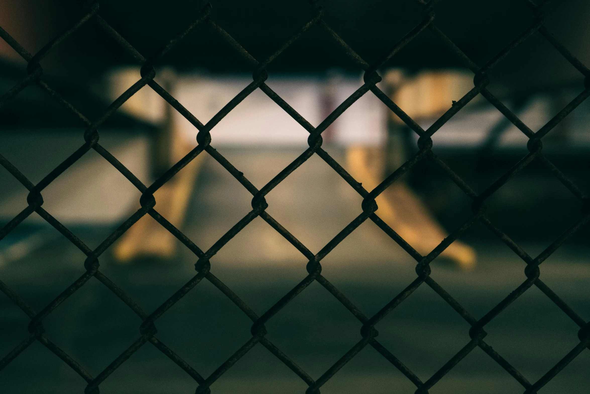 a blurry image of a yellow table behind a metal fence