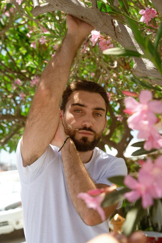 a man with a beard and white shirt holding on to a pink flower