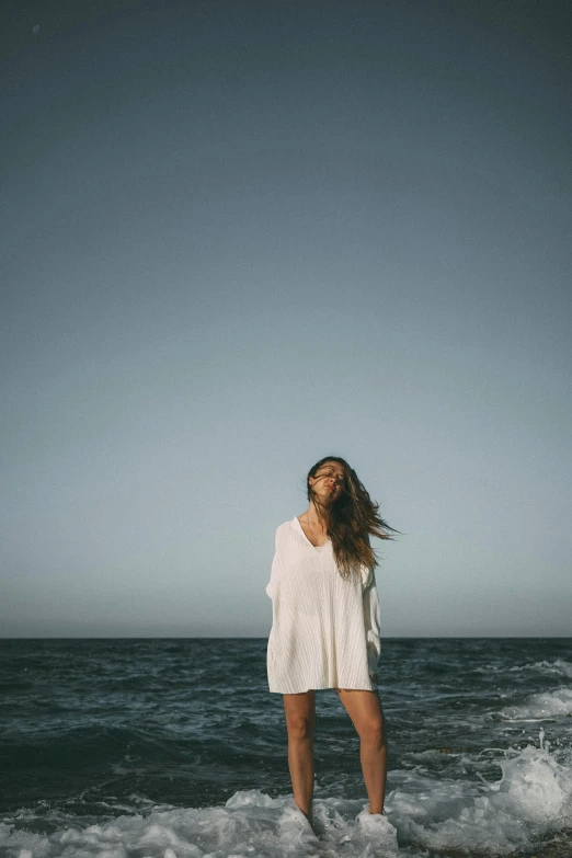 a woman is standing in the surf on a cloudy day