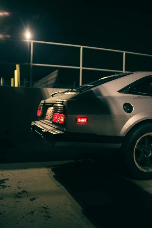 silver sport car parked in a parking lot at night