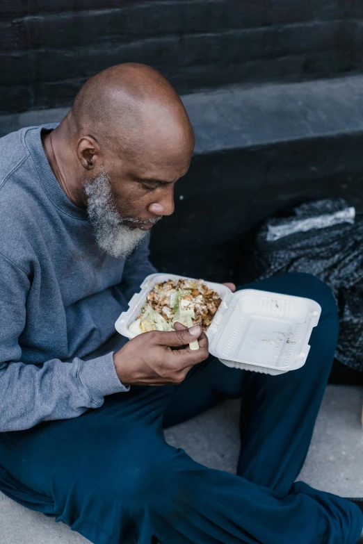 man sitting and eating a sandwich with a cigarette