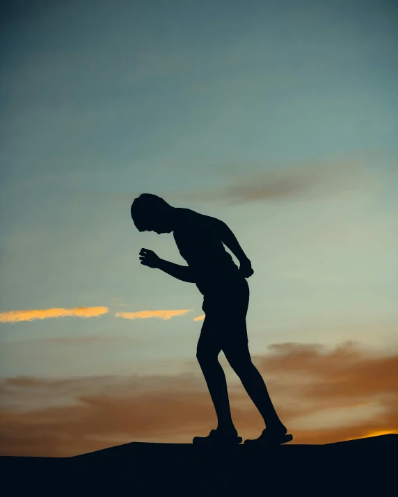 man standing on top of a hill in silhouette using his phone