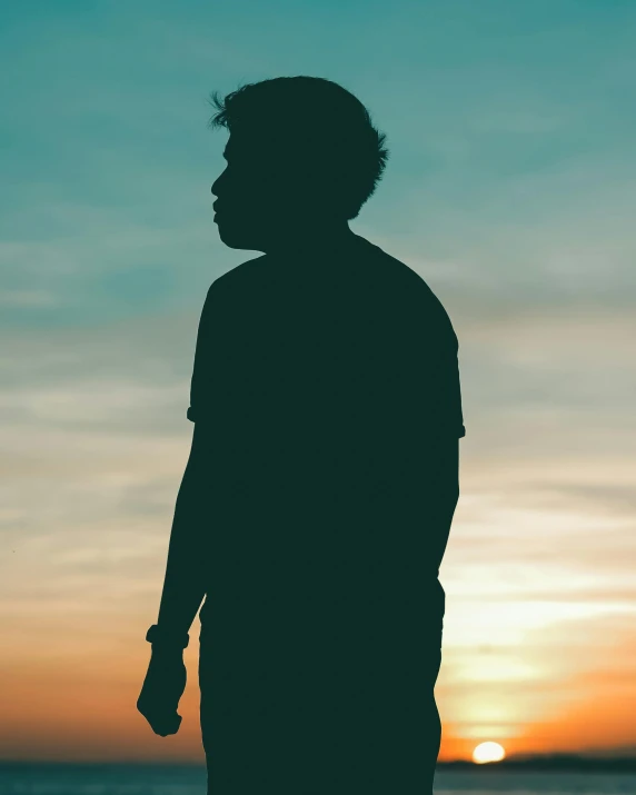 the silhouette of a man stands alone at sunset