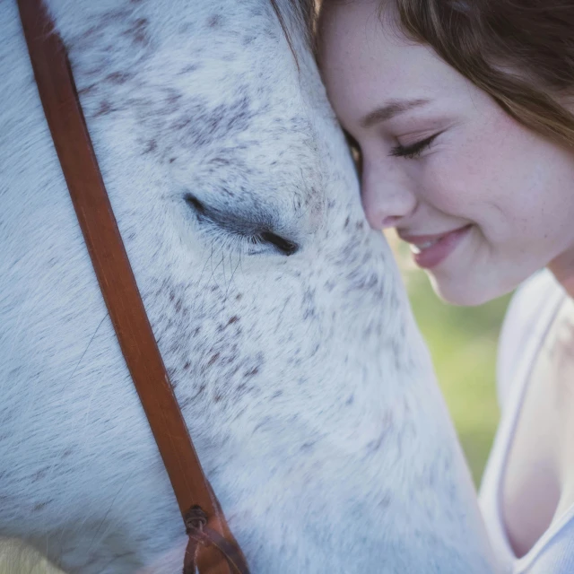a girl is petting the head of a horse