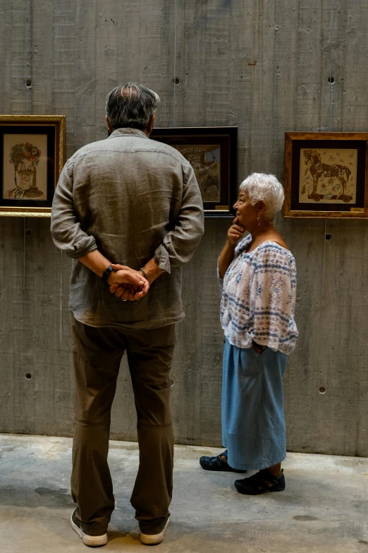 a man and a woman standing in front of a couple of pictures