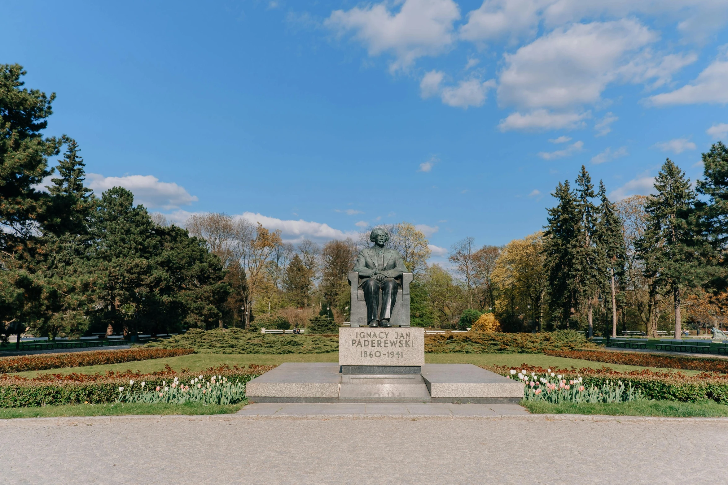 a garden with a statue surrounded by flowers and a flower bed