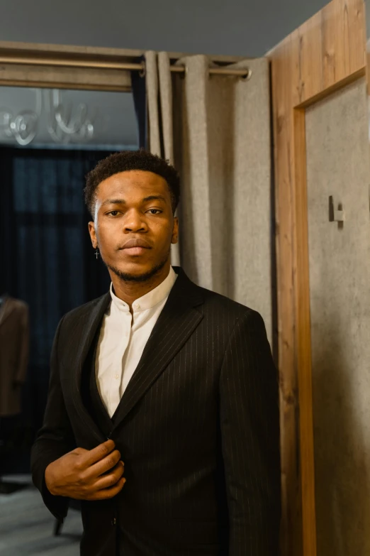 a man in a suit standing next to the door of his room