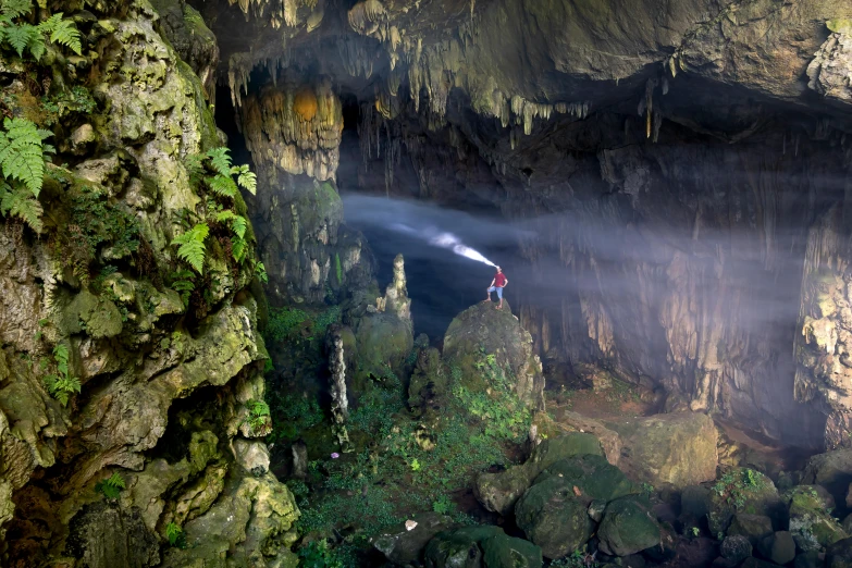 person standing at top of cliff with flashlight on head