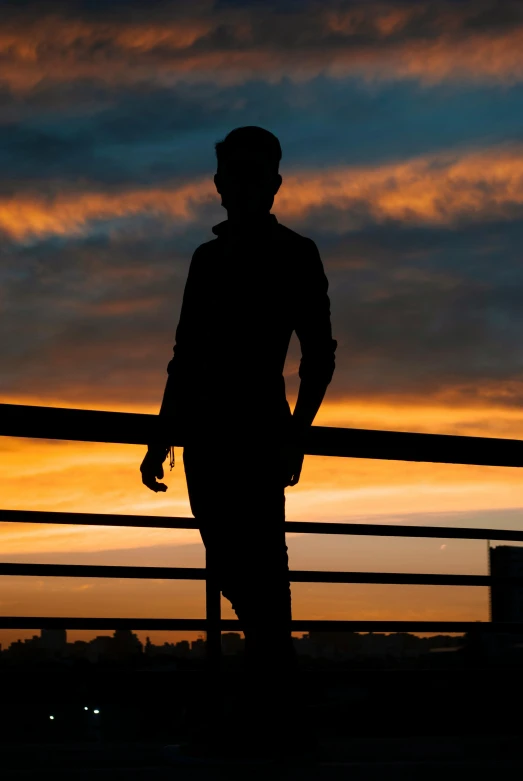 a silhouette po of someone standing on a fence