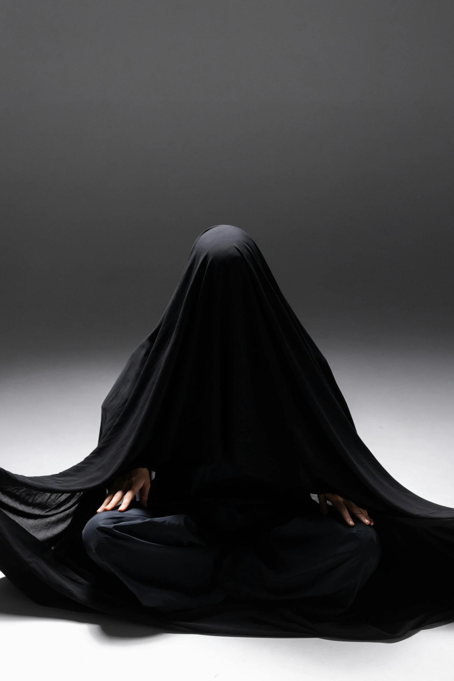 a woman in black veil covering her head with her hand