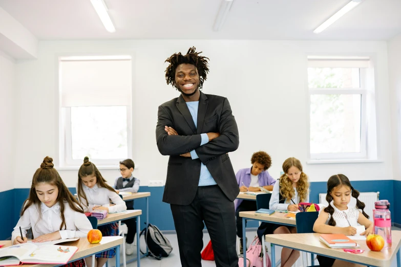 a man stands in a classroom with his arms folded