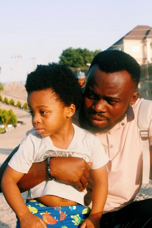 a man in white shirt sitting on top of a child's lap