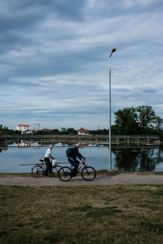 two men riding their bikes together near the water