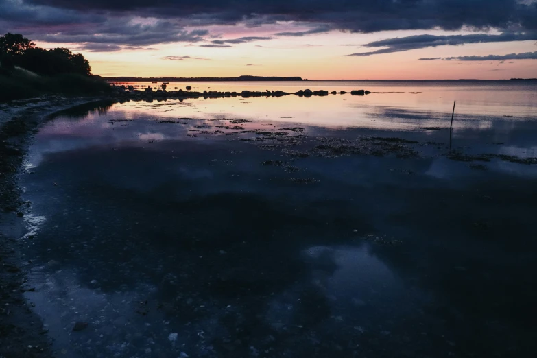 a very long dock with some water reflecting the sunset