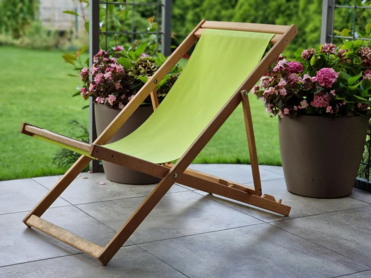 an empty wooden deck chair next to a flower pot