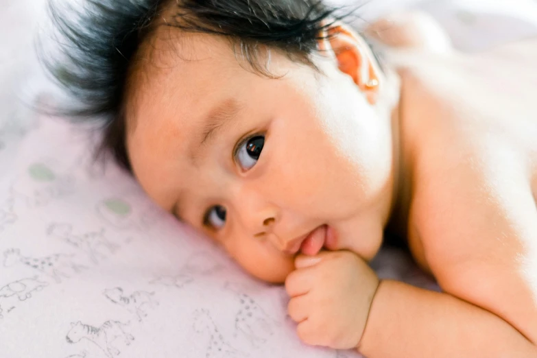 an asian baby laying on top of a blanket