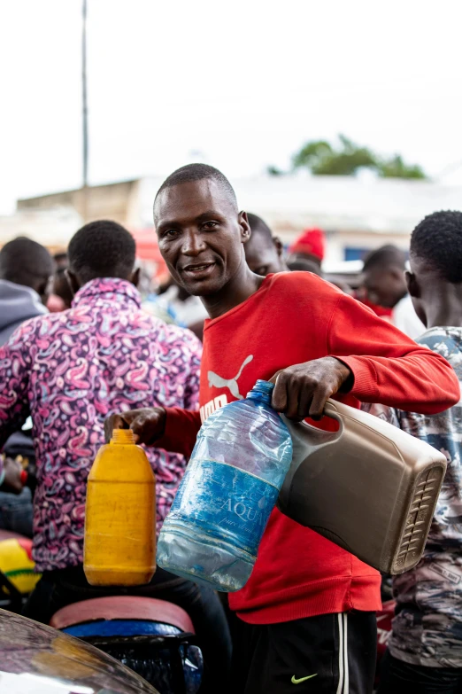 a man with some bottles holding soing in one hand and a bag of water in the other