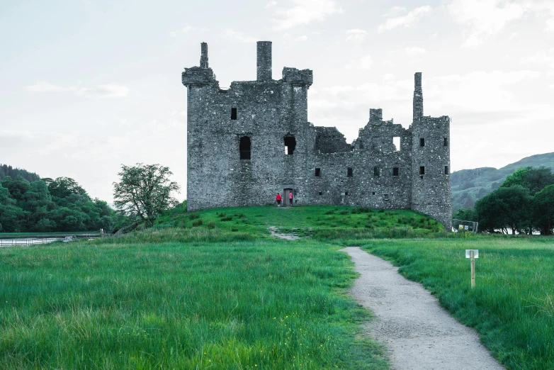 an old castle on a hill is located next to a path