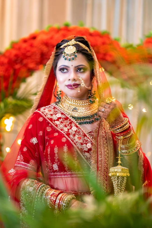 a woman in a red wedding outfit is wearing a bridal and has a yellow choket on