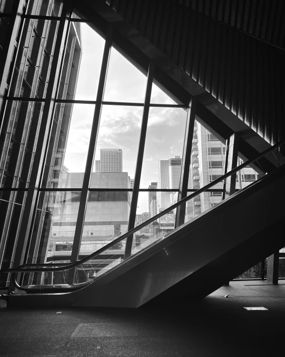 an escalator in an enclosed walkway looking down at some tall buildings