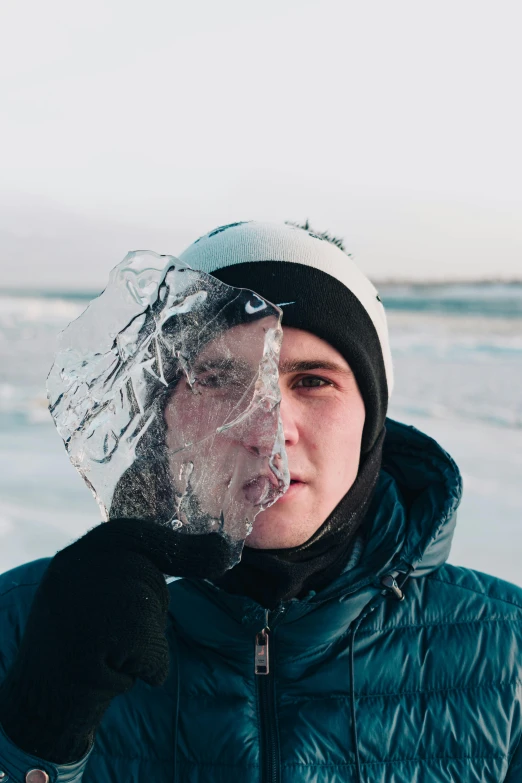a man in blue jacket holding ice on face