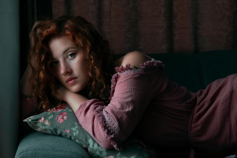 a woman in a purple shirt and green couch with her arm behind her