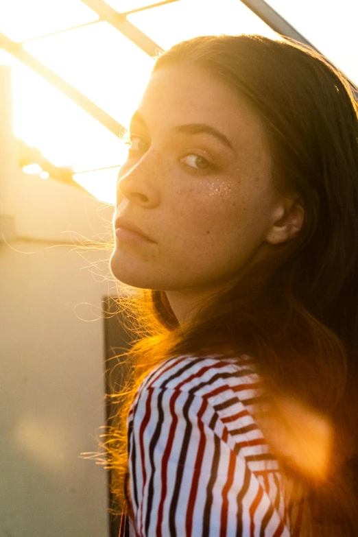 a girl with red and white striped shirt standing in a sun light