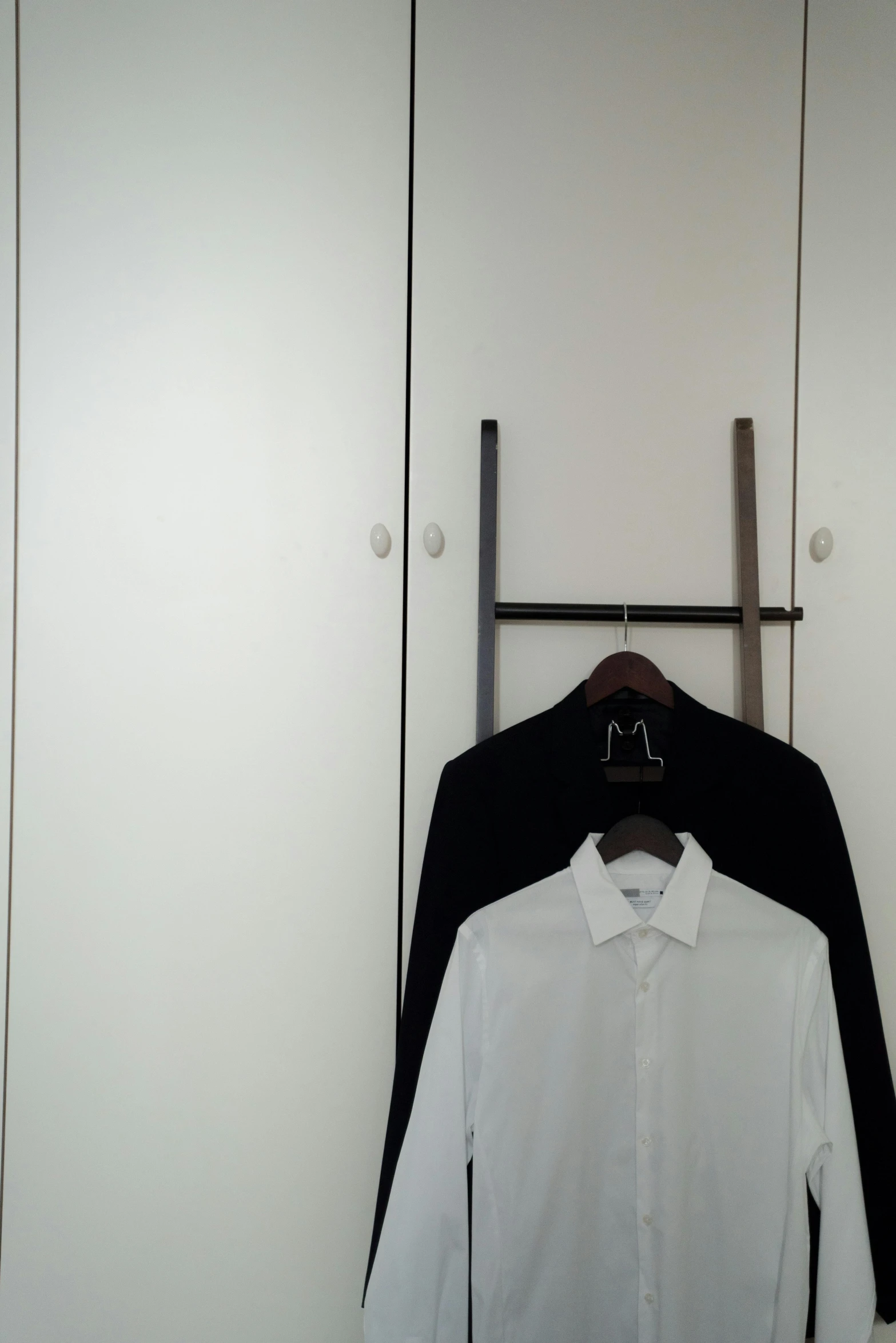 two white shirts hanging on clothes pins on wall